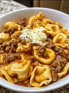 a white bowl filled with pasta and meat