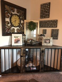 a dog in a cage next to a wall with pictures and a clock on it