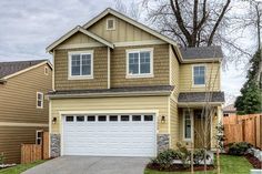 a two story house with brown siding and white garage doors