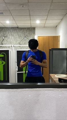 a man standing in front of a mirror looking at his cell phone