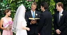 a bride and groom standing next to each other in front of a man holding a book