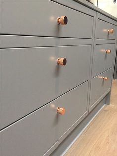 a gray dresser with brass handles and knobs