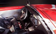 the interior of a red sports car with its steering wheel and dash board up close