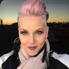 a woman with pink hair wearing a scarf