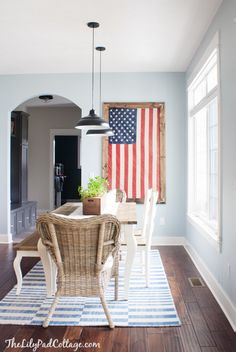 a dining room table with chairs and an american flag hanging on the wall behind it