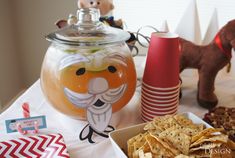 a table topped with lots of food next to a glass jar filled with liquid and crackers