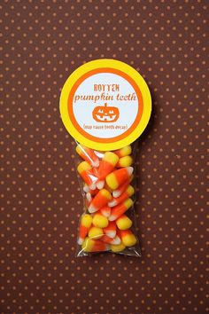 a bag filled with candy corn sitting on top of a brown table next to a polka dot wall