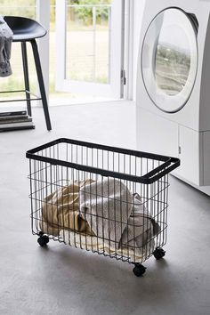 a dog laying in a laundry basket next to a washer and dryer on the floor