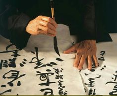 a person with their hands on a piece of paper that has chinese writing on it