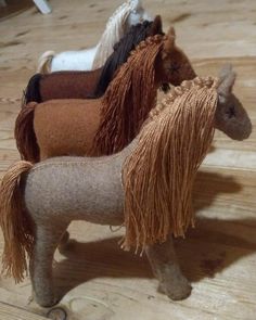 three miniature horses standing on top of a wooden floor next to each other and one horse has long manes