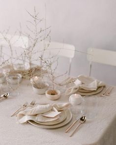 the table is set with white dishes and silverware