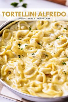 a pan full of tortellini alfredo with cheese and parsley on the side