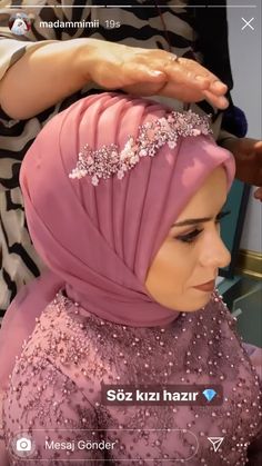 a woman is getting her hair done by another person in a pink hijab