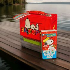 a red cooler and box sitting on top of a wooden dock