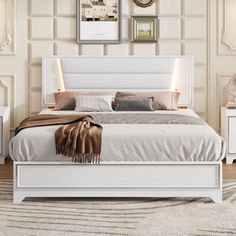 a white bed sitting in a bedroom on top of a wooden floor next to two nightstands