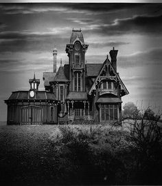 an old house with a clock on the front and side of it in black and white