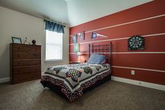 a bed room with a neatly made bed next to a dresser and window in it