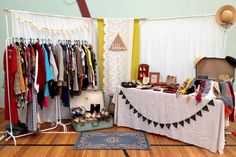 an assortment of clothes and hats on display in a room with wood floors, white curtains, and wooden flooring