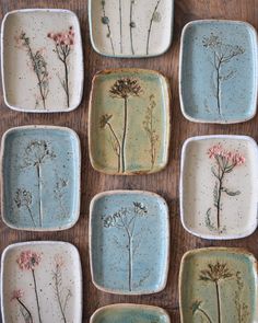 nine plates with flowers painted on them sitting on a wooden table next to each other