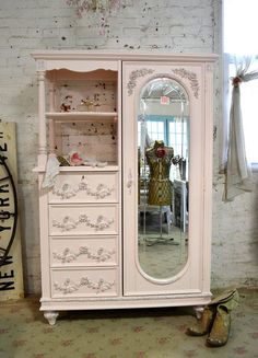 a white china cabinet sitting in front of a window next to a pair of shoes