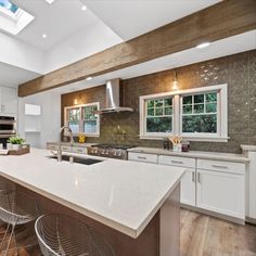 a large kitchen with an island in the middle and two chairs at the counter top