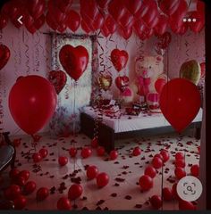 a room filled with lots of red balloons and heart shaped balloons floating in the air