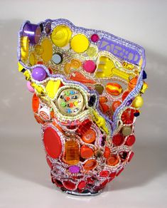 a colorful vase with lots of different things on it's side, including buttons and beads