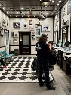 a man is getting his hair cut in a barbershop while another person sits on the chair