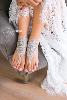 a woman wearing white lace barefoot sandals with her hands on her knees and feet in the air