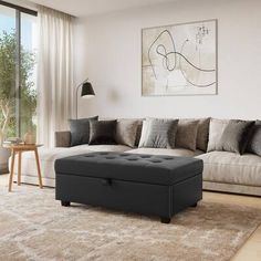 a living room with a couch, ottoman and large window overlooking the trees in the distance