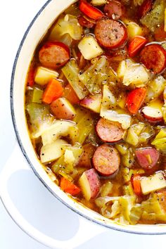 a pot full of soup with sausages, potatoes and carrots