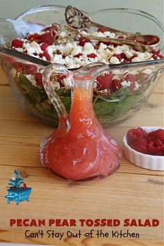 a salad in a glass bowl with feta cheese and raspberries on the side