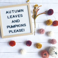 a sign that says autumn leaves and pumpkins please next to yarn balls on a white wooden surface