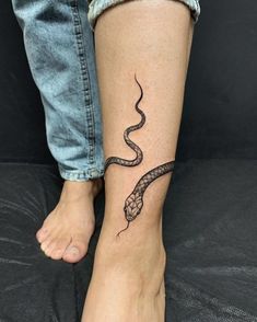 a woman's foot with a snake tattoo on the left side of her leg