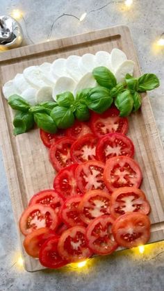 tomatoes, mozzarella and basil on a cutting board with lights in the background