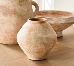 three clay vases sitting on top of a wooden table