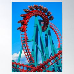 the roller coaster is red and green against a blue sky