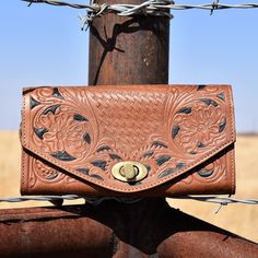 Large tan embossed leather wallet in floral and basket weave prints and painted black detailing. Brass toggle clasp closure on the envelope front flap. Womens Western Hats, Western Bracelets, Tooled Leather Bag, Leopard Bag, Rugged Leather, Leather Weekender Bag, Leather Weekender, Leather Patchwork, Western Hats