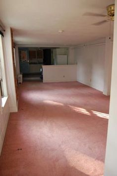 an empty living room with pink carpeting and no one in the house or furniture