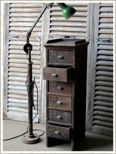 an old wooden drawer with a green lamp on top