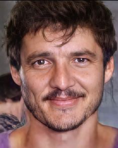 a close up of a person wearing a purple shirt and smiling at the camera with his eyes wide open