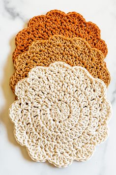 four crocheted coasters on a marble surface