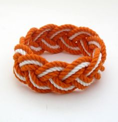 an orange and white rope bracelet on a white background