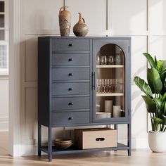 a blue cabinet with glass doors and drawers next to a potted plant