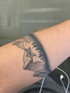 a man's arm with a tattoo on it that has an image of a mountain and a star