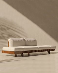 a white couch sitting in the middle of a room next to a wall with shadows on it