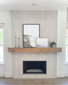 a fireplace with white chevron tile and wood mantle