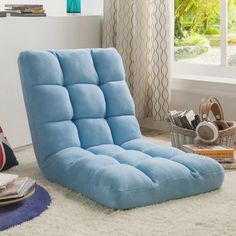 a blue futon chair sitting on top of a white rug next to a window