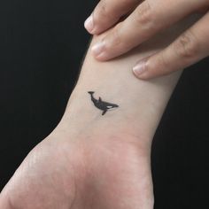 a small black bird tattoo on the wrist