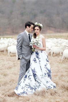 a bride and groom standing in front of a herd of sheep